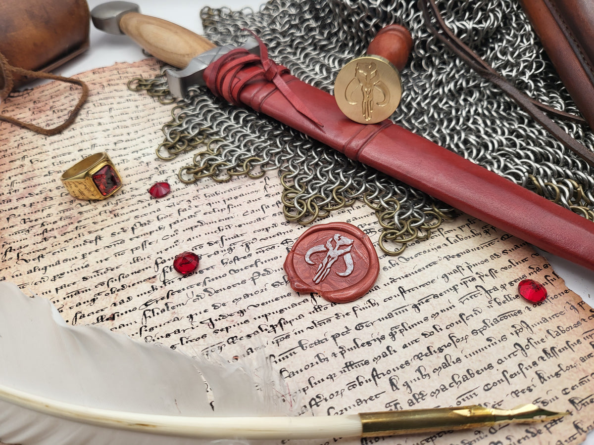 A styled flat-lay of medieval-themed accessories on aged script paper, including a red wax seal, chainmail, a red leather-wrapped letter opener, a gold ring with a red stone, a feather quill, and a gold pen nib.