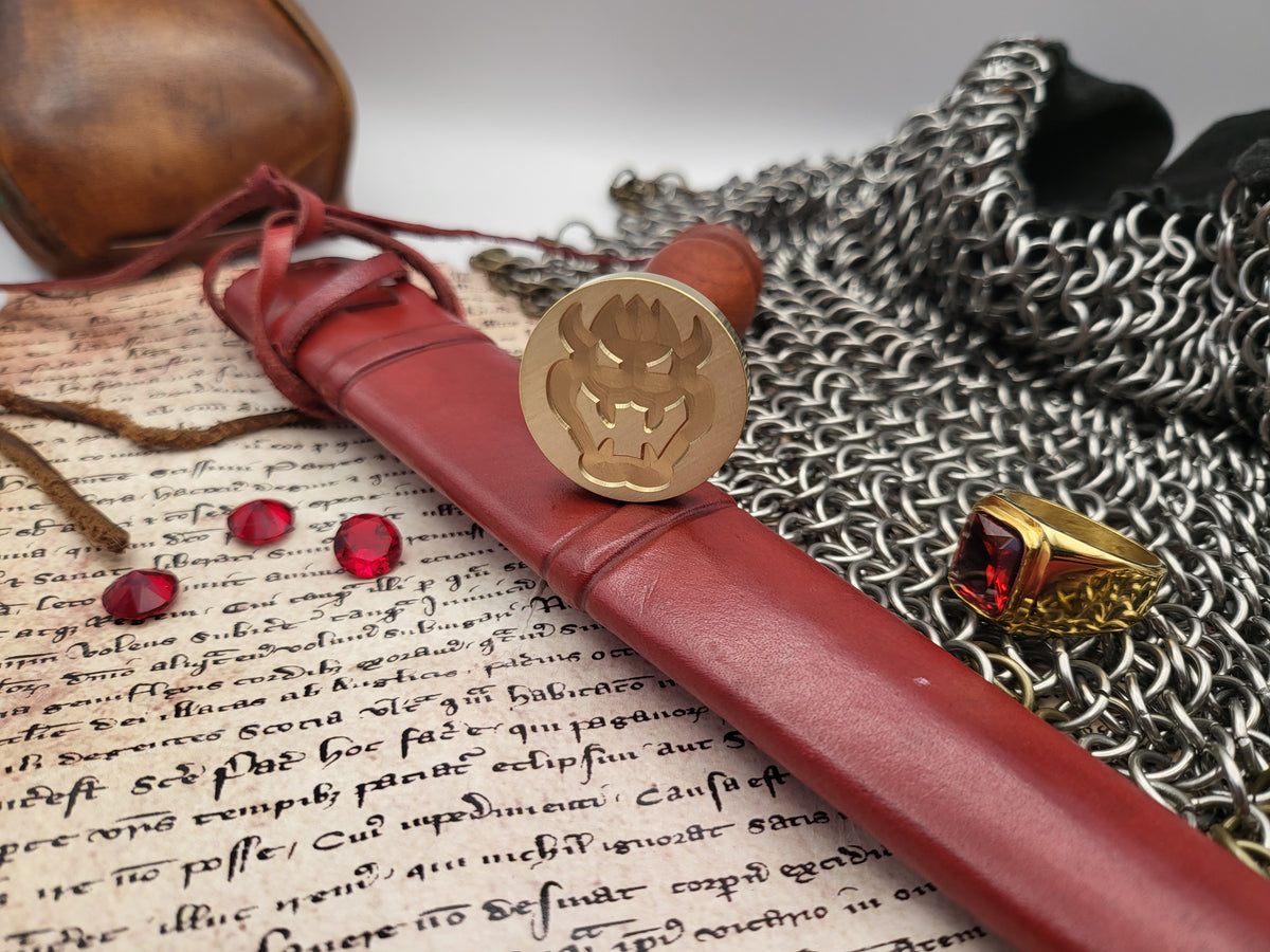A leather-bound seal with a brass seal stamp resting on an open book, surrounded by medieval-themed props including a ring with a red gem, chainmail, and a leather pouch.