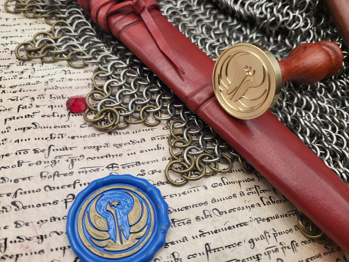 A close-up styled arrangement showing a red leather seal wax envelope with a brass stamp, a blue wax seal with a gold emblem, and chainmail over aged handwritten paper.