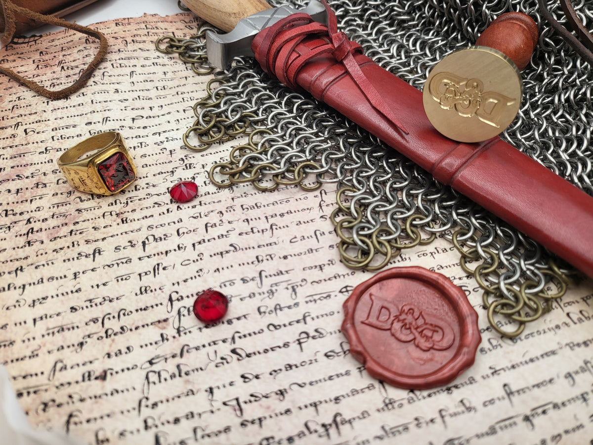 D&D dragon ampersand wax seal impression in red sealing wax beside the brass stamp.