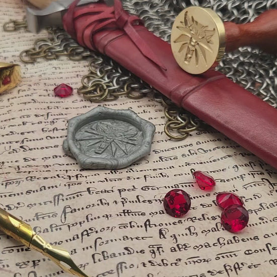 Witcher Wolf brass wax seal stamp displayed on an open book with chainmail.